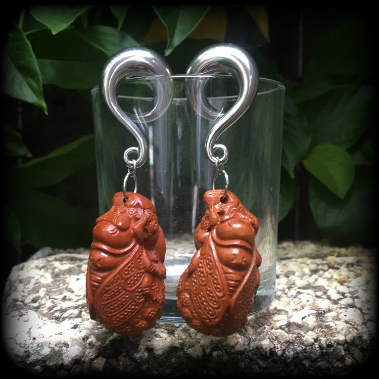 These beautiful gauged earrings feature a carved peach wood cicada, weighing in at 32 grams a piece, and measuring just under 10cms from tip to tip.
This pair has been made on 00 gauge (10mm) surgical steel full curl hooks, for stretched lobes.
