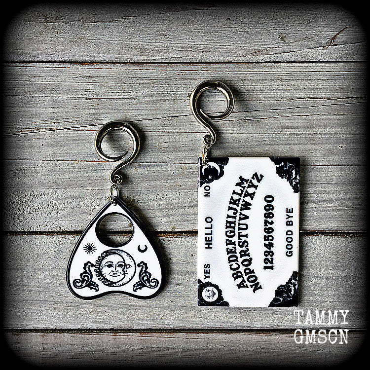 These spooky cute earrings feature black and white double sided acrylic ouija board and planchette charms, weighing approx 7 grams a piece, and measuring 7-9cms from tip to tip.

These have been made on 6 gauge (4mm) surgical steel full curl hooks, to be worn in stretched lobes.