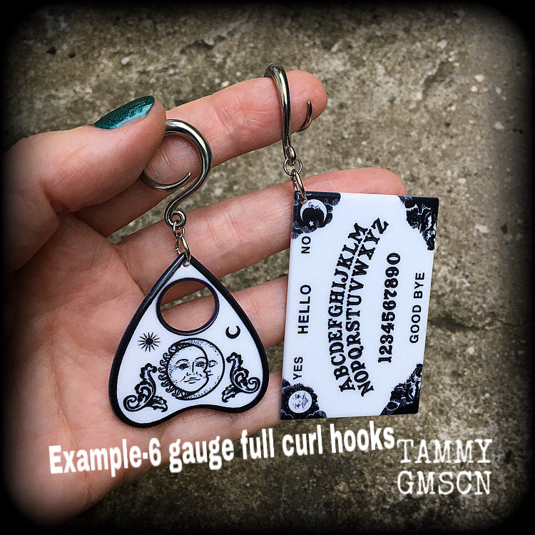 These spooky cute earrings feature black and white double sided acrylic ouija board and planchette charms, weighing approx 7 grams a piece, and measuring 7-9cms from tip to tip.

These have been made on 6 gauge (4mm) surgical steel full curl hooks, to be worn in stretched lobes.