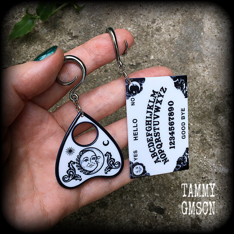 These spooky cute earrings feature black and white double sided acrylic ouija board and planchette charms, weighing approx 7 grams a piece, and measuring 7-9cms from tip to tip.

These have been made on 6 gauge (4mm) surgical steel full curl hooks, to be worn in stretched lobes.