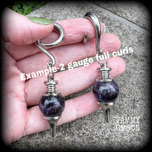 Featuring a pair of beautiful plump purple amethyst pendulums, this pair of earrings weighs approx 21 grams a piece and measure just over 7cms from tip to tip.
This pair have been made on 2 gauge (6mm) surgical steel full curl hooks, to be worn in stretched lobes.
