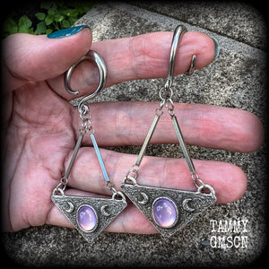 Featuring an inverted triangle with crescent moons and a single translucent purple cabachon, measuring just over 7 cms from tip to tip, and weighing approx 8 grams each.
This pair has been made on 6 gauge (4mm) surgical steel full curl hooks.
