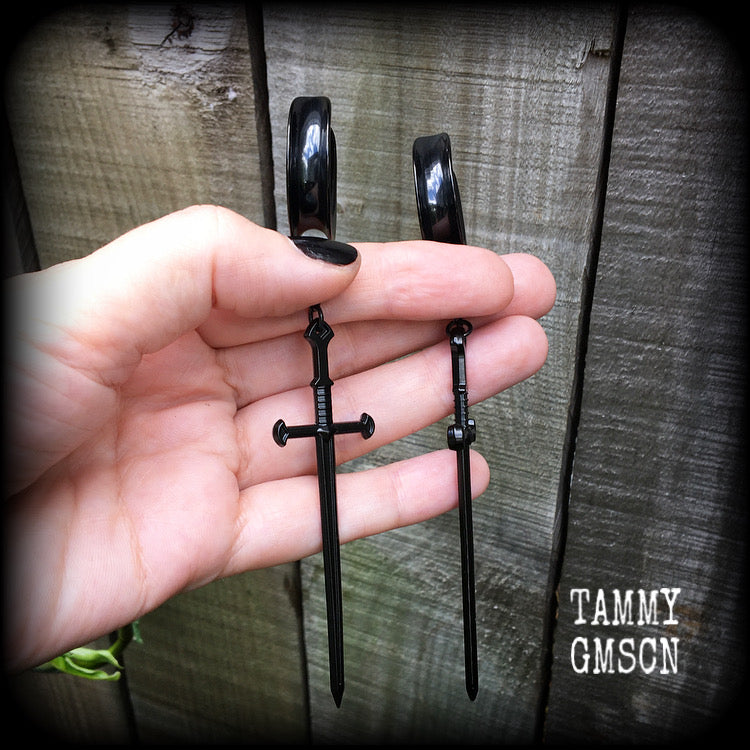 These gorgeous ear hangers feature a pitch black enamel sword pendant, measuring just on 12cms from tip to tip, and weighing approx 12 grams each.
This pair has been made on 1" (25mm) surgical steel cradle hooks, to be worn in stretched lobes.