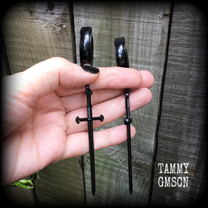 These gorgeous ear hangers feature a pitch black enamel sword pendant, measuring just on 12cms from tip to tip, and weighing approx 12 grams each.
This pair has been made on 1" (25mm) surgical steel cradle hooks, to be worn in stretched lobes.