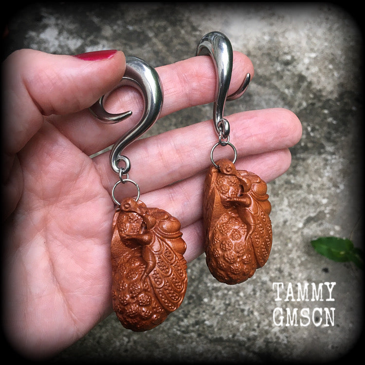 These beautiful gauged earrings feature a carved peach wood cicada, weighing in at 32 grams a piece, and measuring just under 10cms from tip to tip.
This pair has been made on 00 gauge (10mm) surgical steel full curl hooks, for stretched lobes.
