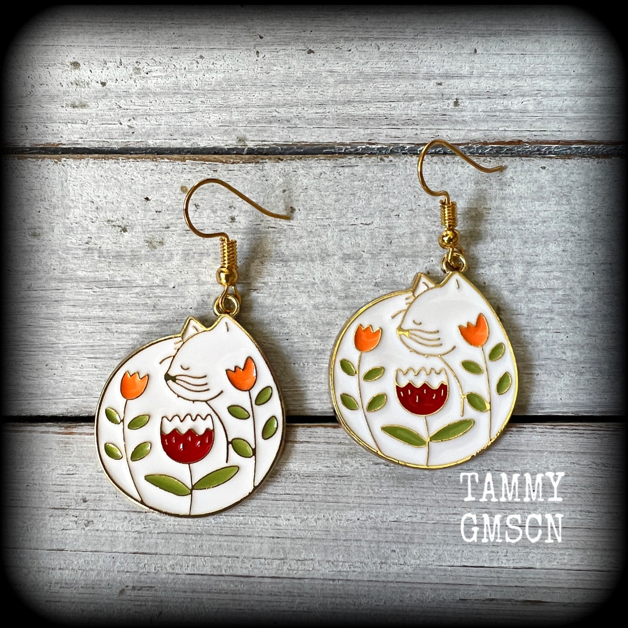 These adorably quirky earrings feature gorgeous folk art inspired cat and tulip charms.
Measuring 5cms from tip to tip, these earrings are nice and lightweight at only 4 grams each.
This pair has been made on antique gold french hooks, to be worn in pierced ears.