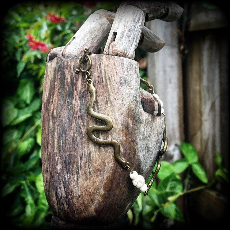 Featuring three antique bronze snake charms moulded to fit your wrist with small bone white howlite stone beads, this bracelet measures just on 20cms from tip to tip when laid flat and fastens with a bronze tone toggle clasp.
