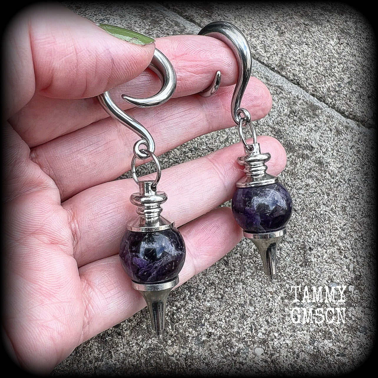 Featuring a pair of beautiful plump purple amethyst pendulums, this pair of earrings weighs approx 21 grams a piece and measure just over 7cms from tip to tip.
This pair have been made on 2 gauge (6mm) surgical steel full curl hooks, to be worn in stretched lobes.