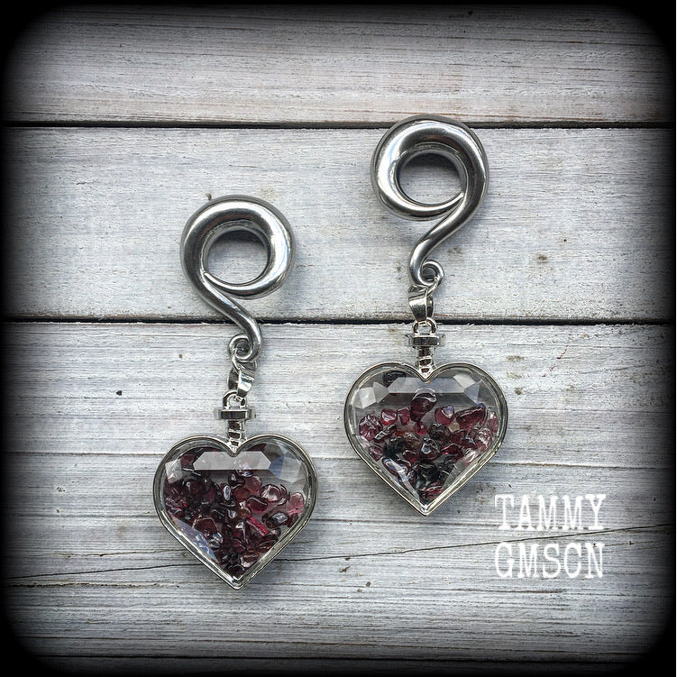 Heart shaped glass bottles filled with garnet gemstone chips, available on a range of hooks and clasps for pierced ears and stretched lobes.