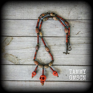 Featuring three dirty jaffa stone skull bead drops, Chocolate jasper barrel beads and dirt brown howlite stone beads, dotted with antique bronze beads, this necklace is one of the more elaborate in the Papa Legba range.
Measuring 52cm from end to end when laid flat, this necklace fastens with an antique bronze toggle clasp.