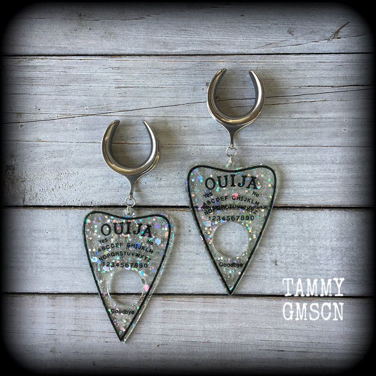 Featuring large glittery acrylic ouija board planchettes, this pair of gorgeous earrings weighs approx 10 grams a piece, and measure 10cms from tip to tip.

This pair has been made with 3/4" gauge (19mm) surgical steel cradle hooks, for stretched lobes.