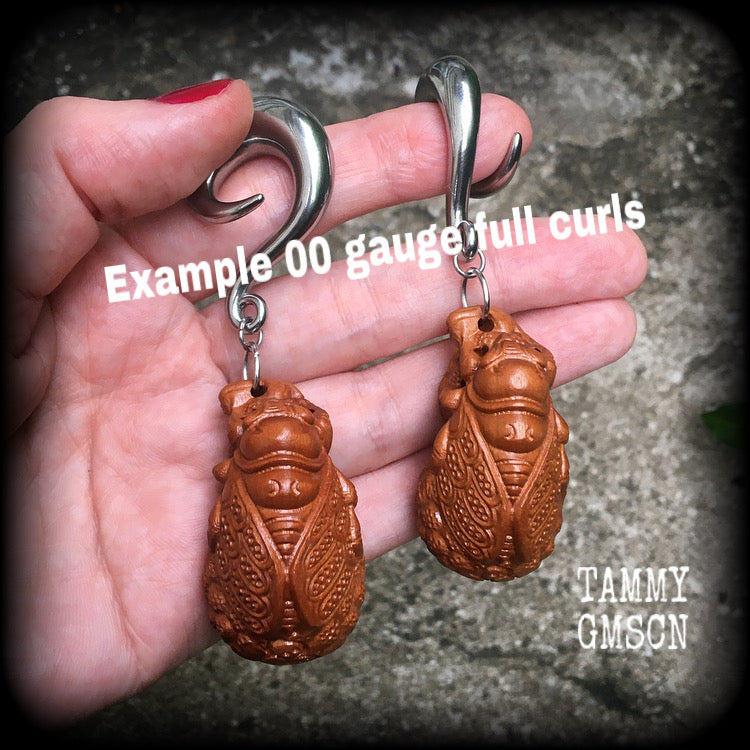 These beautiful gauged earrings feature a carved peach wood cicada, weighing in at 32 grams a piece, and measuring just under 10cms from tip to tip.
This pair has been made on 00 gauge (10mm) surgical steel full curl hooks, for stretched lobes.
