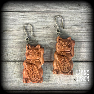 These earrings feature carved rose wood Maneki Neko cats, measure 8cms from tip to tip, and weigh approx 8 grams each.
These are made on small antique silver shephard hooks, for stretched lobes when worn with silicone earlets from 8 gauge (3mm). 