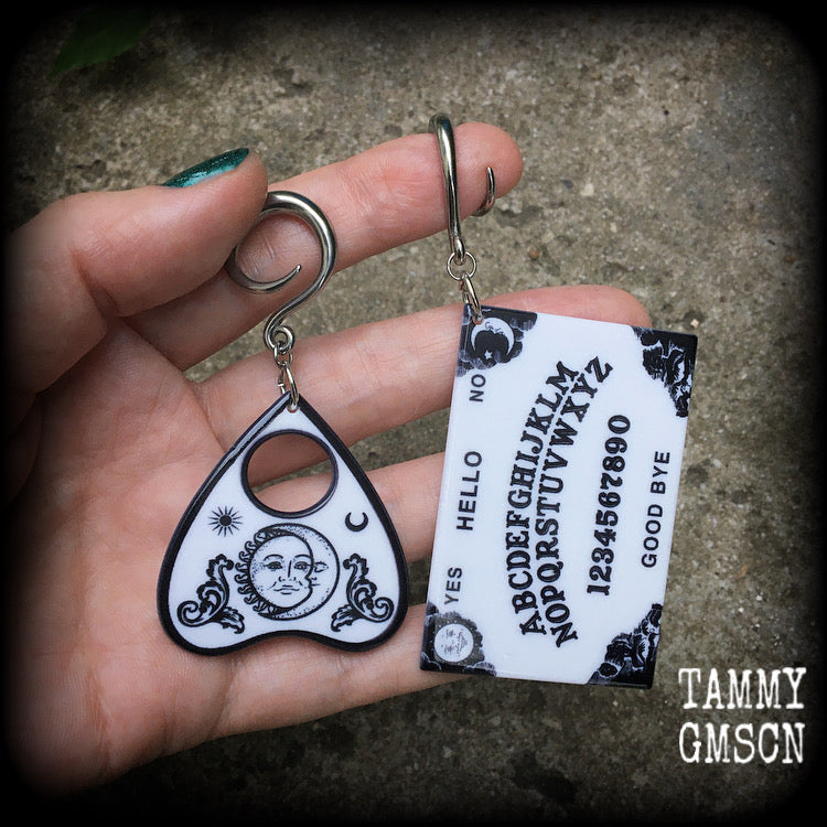 These spooky cute earrings feature black and white double sided acrylic ouija board and planchette charms, weighing approx 7 grams a piece, and measuring 7-9cms from tip to tip.

These have been made on 6 gauge (4mm) surgical steel full curl hooks, to be worn in stretched lobes.