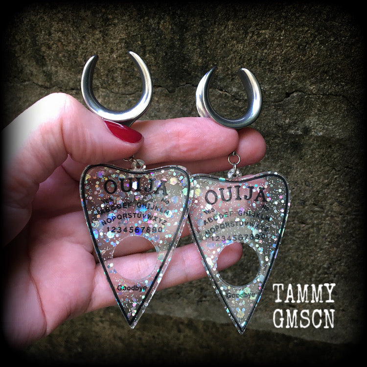 Featuring large glittery acrylic ouija board planchettes, this pair of gorgeous earrings weighs approx 10 grams a piece, and measure 10cms from tip to tip.

This pair has been made with 3/4" gauge (19mm) surgical steel cradle hooks, for stretched lobes.