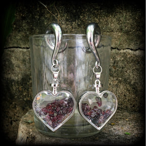 Heart shaped glass bottles filled with garnet gemstone chips, available on a range of hooks and clasps for pierced ears and stretched lobes.