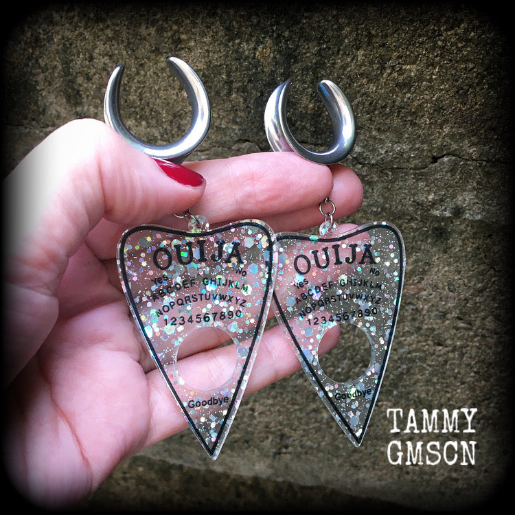 Featuring large glittery acrylic ouija board planchettes, this pair of gorgeous earrings weighs approx 10 grams a piece, and measure 10cms from tip to tip.

This pair has been made with 3/4" gauge (19mm) surgical steel cradle hooks, for stretched lobes.