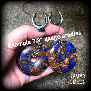Featuring a pair of gorgeous dark blue lapis lazuli and bronzite donut gemstones cradles in stainless steel chain, this pair of ear hangers weigh approx 34 grams a piece, and measure just under 10cms from tip to tip.
This pair have been made on 7/8" (22mm) gauge surgical steel cradles, for stretched lobes.