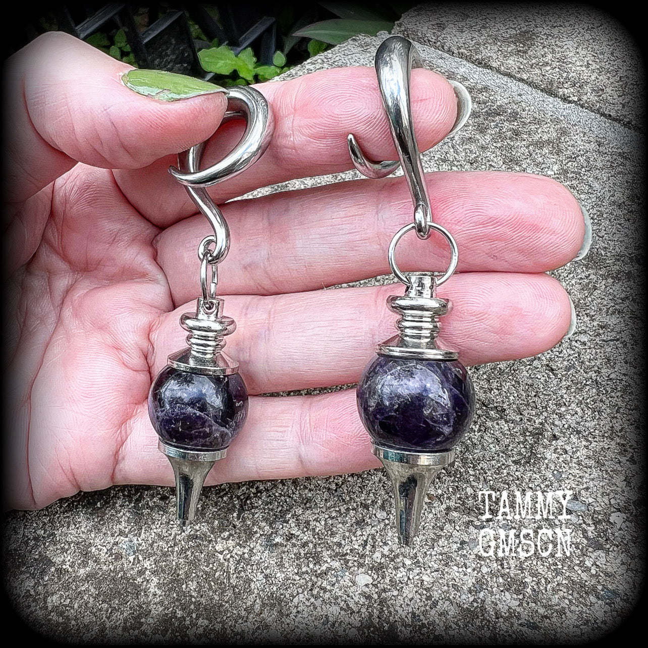 Featuring a pair of beautiful plump purple amethyst pendulums, this pair of earrings weighs approx 21 grams a piece and measure just over 7cms from tip to tip.
This pair have been made on 2 gauge (6mm) surgical steel full curl hooks, to be worn in stretched lobes.