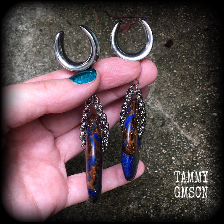 Featuring a pair of gorgeous dark blue lapis lazuli and bronzite donut gemstones cradles in stainless steel chain, this pair of ear hangers weigh approx 34 grams a piece, and measure just under 10cms from tip to tip.
This pair have been made on 7/8" (22mm) gauge surgical steel cradles, for stretched lobes.