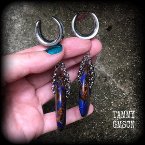 Featuring a pair of gorgeous dark blue lapis lazuli and bronzite donut gemstones cradles in stainless steel chain, this pair of ear hangers weigh approx 34 grams a piece, and measure just under 10cms from tip to tip.
This pair have been made on 7/8" (22mm) gauge surgical steel cradles, for stretched lobes.