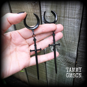 These gorgeous ear hangers feature a pitch black enamel sword pendant, measuring just on 12cms from tip to tip, and weighing approx 12 grams each.
This pair has been made on 1" (25mm) surgical steel cradle hooks, to be worn in stretched lobes.