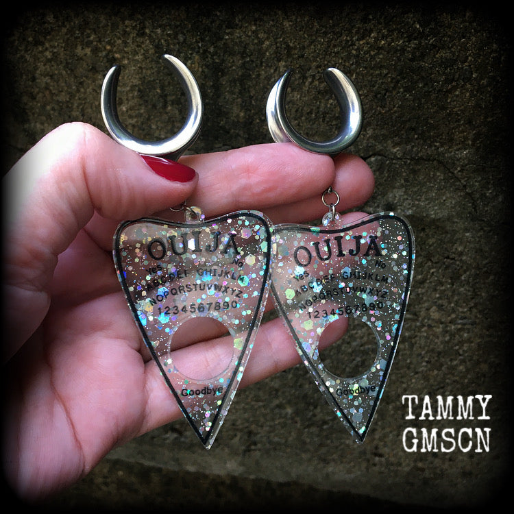 Featuring large glittery acrylic ouija board planchettes, this pair of gorgeous earrings weighs approx 10 grams a piece, and measure 10cms from tip to tip.

This pair has been made with 3/4" gauge (19mm) surgical steel cradle hooks, for stretched lobes.