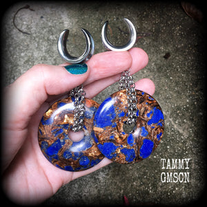 Featuring a pair of gorgeous dark blue lapis lazuli and bronzite donut gemstones cradles in stainless steel chain, this pair of ear hangers weigh approx 34 grams a piece, and measure just under 10cms from tip to tip.
This pair have been made on 7/8" (22mm) gauge surgical steel cradles, for stretched lobes.