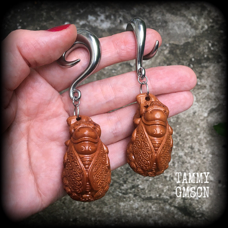 These beautiful gauged earrings feature a carved peach wood cicada, weighing in at 32 grams a piece, and measuring just under 10cms from tip to tip.
This pair has been made on 00 gauge (10mm) surgical steel full curl hooks, for stretched lobes.
