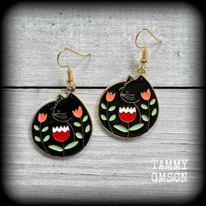 These quirky earrings and feature gorgeous folk art inspired black cat and tulip charms.
These earrings are nice and lightweight at only 4 grams, and measure just on 5cms from tip to tip.
This pair has been made with antique gold french hooks, to be worn in pierced ears.