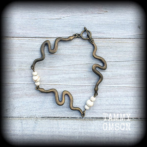 Featuring 3 antique bronze snake charms moulded to fit your wrist with small bone white howlite stone beads, this bracelet measures just on 20cms from tip to tip when laid flat and fastens with a bronze tone toggle clasp.
