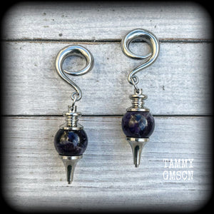 Featuring a pair of beautiful plump purple amethyst pendulums, this pair of earrings weighs approx 21 grams a piece and measure just over 7cms from tip to tip.
This pair have been made on 2 gauge (6mm) surgical steel full curl hooks, to be worn in stretched lobes.