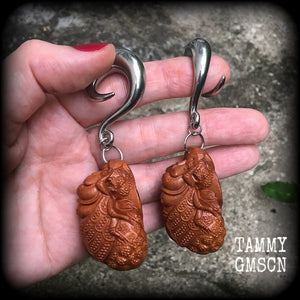 These beautiful gauged earrings feature a carved peach wood cicada, weighing in at 32 grams a piece, and measuring just under 10cms from tip to tip.
This pair has been made on 00 gauge (10mm) surgical steel full curl hooks, for stretched lobes.
