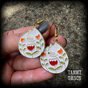 These adorably quirky earrings feature gorgeous folk art inspired cat and tulip charms.
Measuring 5cms from tip to tip, these earrings are nice and lightweight at only 4 grams each.
This pair has been made on antique gold french hooks, to be worn in pierced ears.