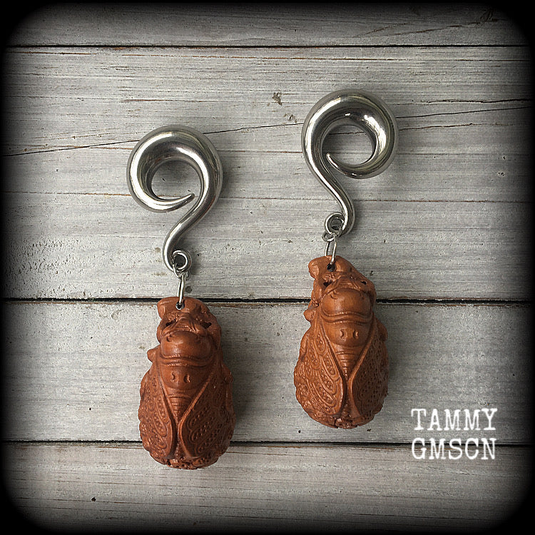 These beautiful gauged earrings feature a carved peach wood cicada, weighing in at 32 grams a piece, and measuring just under 10cms from tip to tip.
This pair has been made on 00 gauge (10mm) surgical steel full curl hooks, for stretched lobes.
