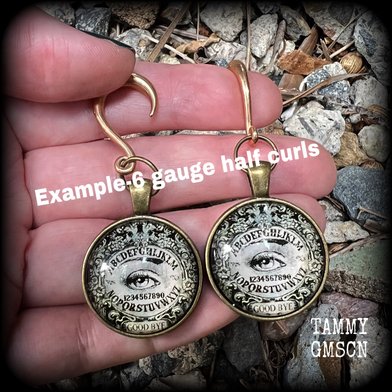 These gorgeous one of a kind Ouija board gauged earrings feature an antique bronze cabachon charm showing a classic ouija board image complete with the all seeing Mystic eye.

These earrings measure just on 6.5cms from tip to tip, and weigh approx 11 grams each.

This pair has been made on 6 gauge (4mm) stainless steel half curl hooks, suitable for stretched lobes.