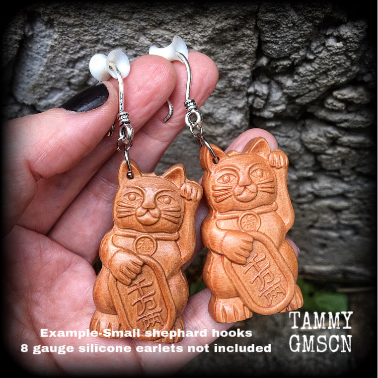 These earrings feature carved rose wood Maneki Neko cats, measure 8cms from tip to tip, and weigh approx 8 grams each.
These are made on small antique silver shephard hooks, for stretched lobes when worn with silicone earlets from 8 gauge (3mm). 