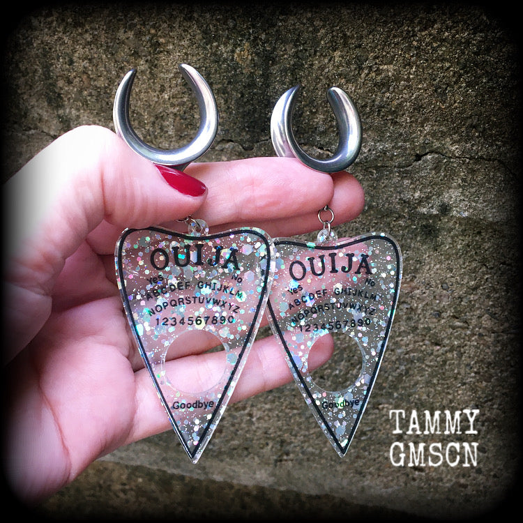 Featuring large glittery acrylic ouija board planchettes, this pair of gorgeous earrings weighs approx 10 grams a piece, and measure 10cms from tip to tip.

This pair has been made with 3/4" gauge (19mm) surgical steel cradle hooks, for stretched lobes.