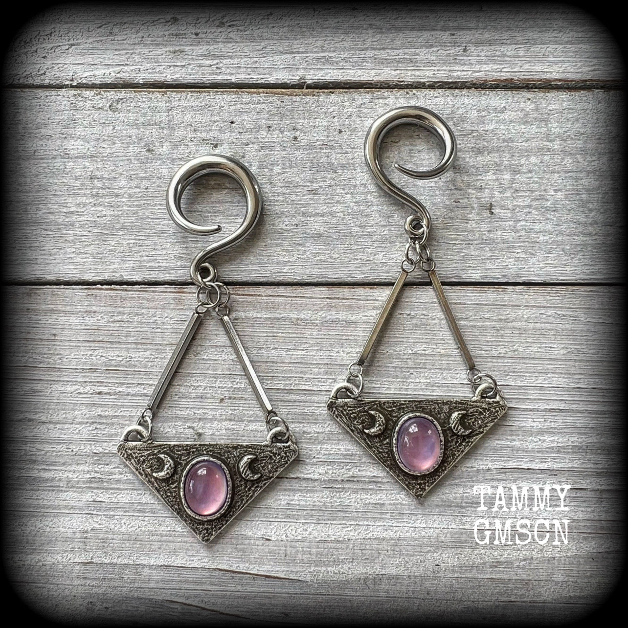 Featuring an inverted triangle with crescent moons and a single translucent purple cabachon, measuring just over 7 cms from tip to tip, and weighing approx 8 grams each.
This pair has been made on 6 gauge (4mm) surgical steel full curl hooks.