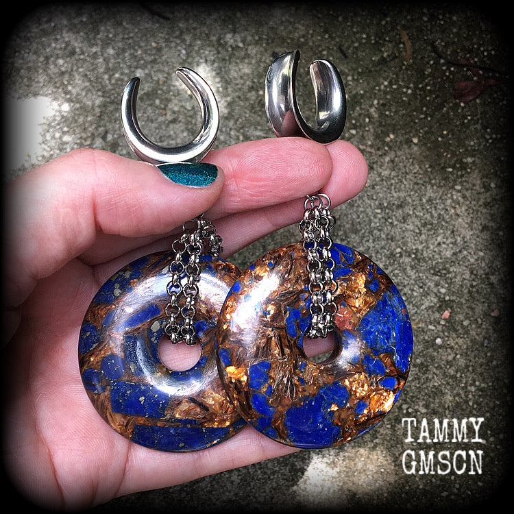 Featuring a pair of gorgeous dark blue lapis lazuli and bronzite donut gemstones cradles in stainless steel chain, this pair of ear hangers weigh approx 34 grams a piece, and measure just under 10cms from tip to tip.
This pair have been made on 7/8" (22mm) gauge surgical steel cradles, for stretched lobes.