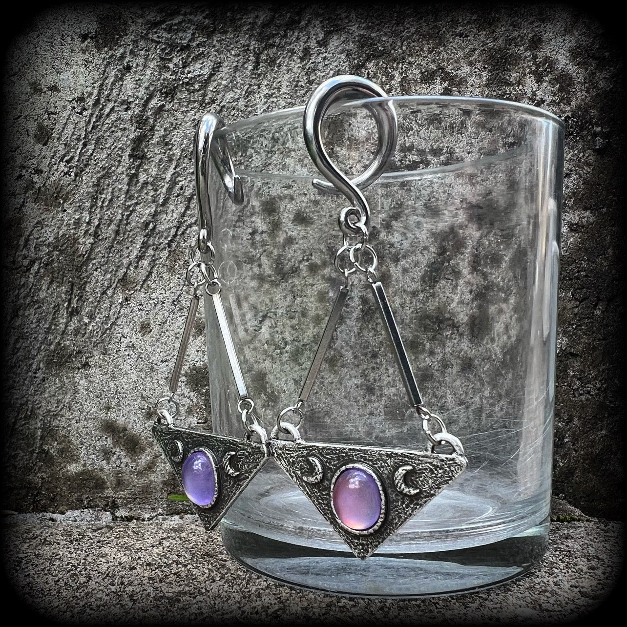 Featuring an inverted triangle with crescent moons and a single translucent purple cabachon, measuring just over 7 cms from tip to tip, and weighing approx 8 grams each.
This pair has been made on 6 gauge (4mm) surgical steel full curl hooks.