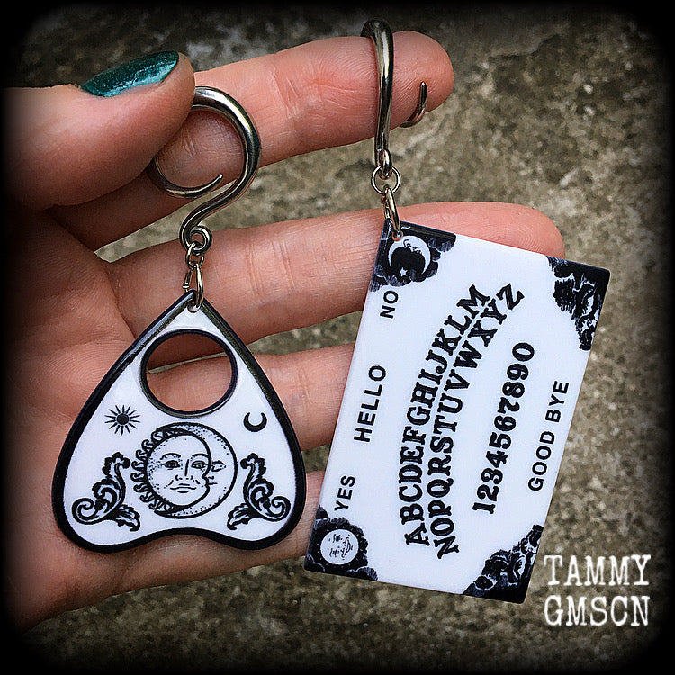 These spooky cute earrings feature black and white double sided acrylic ouija board and planchette charms, weighing approx 7 grams a piece, and measuring 7-9cms from tip to tip.

These have been made on 6 gauge (4mm) surgical steel full curl hooks, to be worn in stretched lobes.