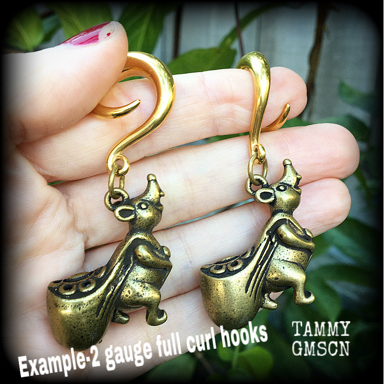 May include: Two gold-colored ear gauges with a dangling chinese money rat charm. Each rat charm is holding a small, round, gold-colored bag. The text 'TAMMY GMSCN' is visible at the bottom of the image.