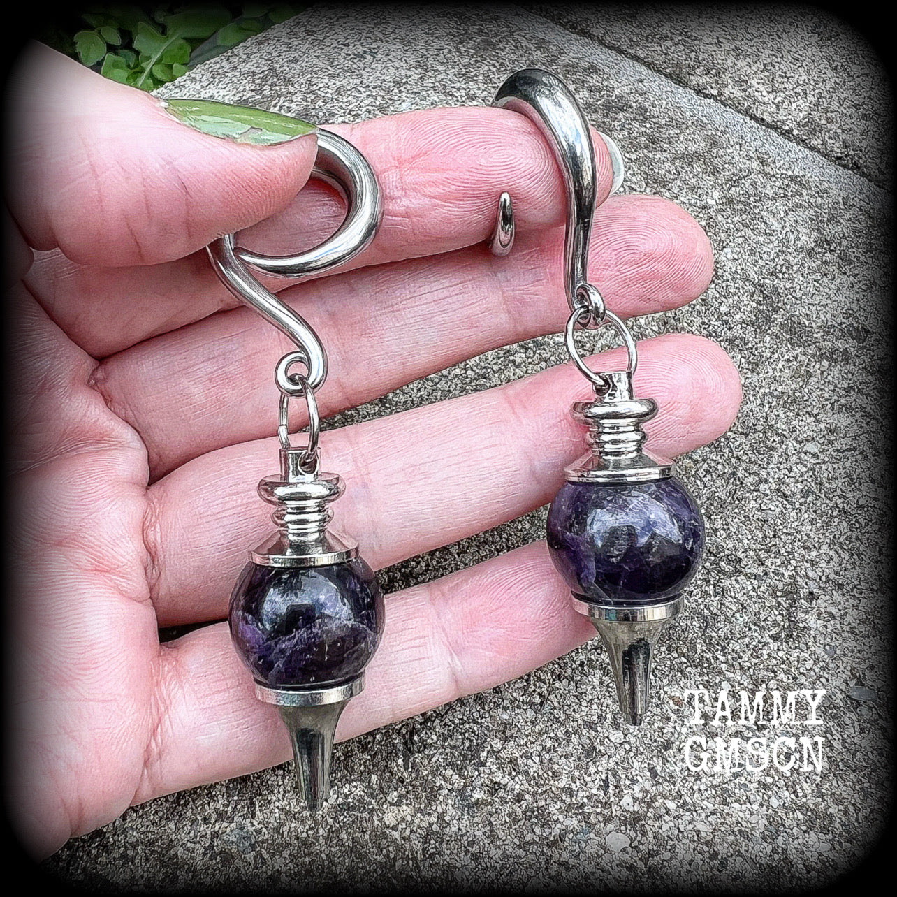 Featuring a pair of beautiful plump purple amethyst pendulums, this pair of earrings weighs approx 21 grams a piece and measure just over 7cms from tip to tip.
This pair have been made on 2 gauge (6mm) surgical steel full curl hooks, to be worn in stretched lobes.